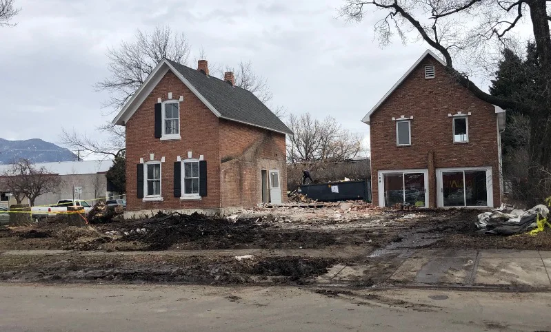 Two brick buildings during restoration with exposed ground between them