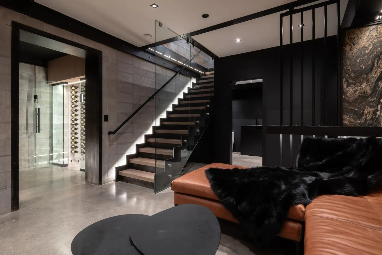 Ultra-modern Rouse House interior with a glass staircase, concrete walls and dark architectural finishes